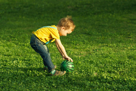 可爱的积极孩子,绿色的草地上的球玩得很开心照片