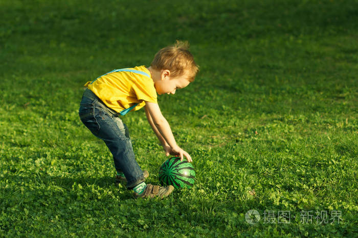 可爱的积极孩子,绿色的草地上的球玩得很开心
