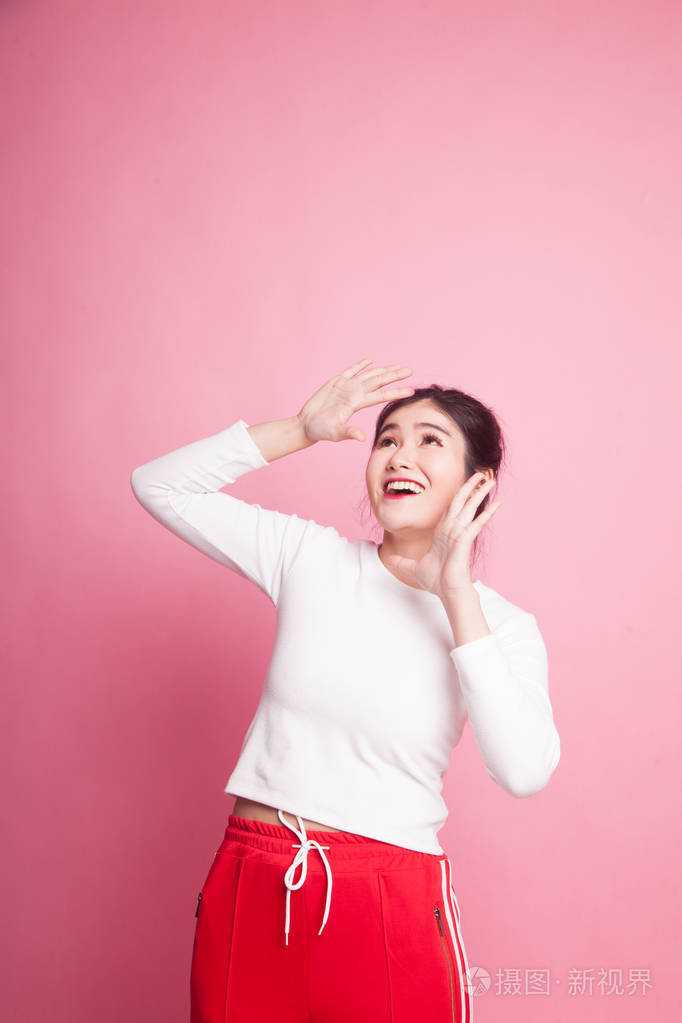 兴奋的年轻亚洲妇女仰望粉红色背景