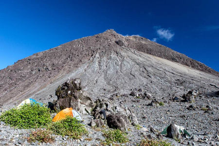 在默拉皮火山的斜坡上露营在默拉皮火山火山熔岩圆顶帐篷前