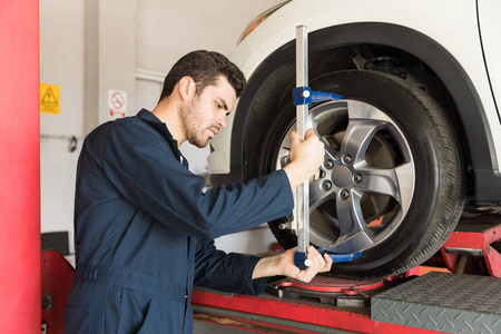 维修工程师在车库中用弧形脚轮适配器检查轮胎的对准