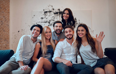 一群年轻人在一起玩得很开心.坐在沙发上的亲密朋友大公司照片