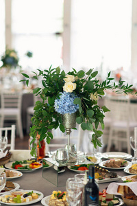 宴会桌上装饰着绣球花和绿叶的构图。