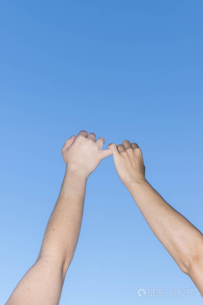 在晴朗的蓝天下手持双手的年轻人特写