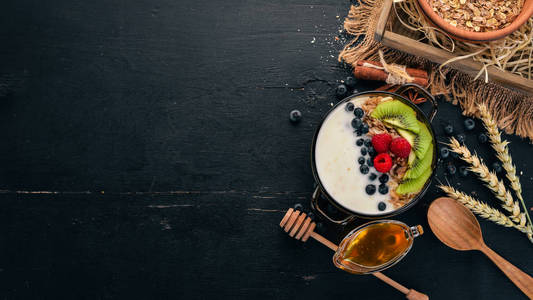 燕麦片配酸奶水果和浆果。猕猴桃, 蓝莓, 覆盆子。在一个木质的背景。顶部视图。文本的可用空间