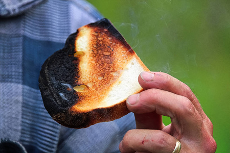 一只手捧着烤面包, 部分烧焦了照片