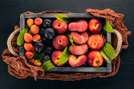 新鲜水果在一个木箱里。杏, 桃子, 油桃, 李子。在一个木质的背景。顶部视图。文本的可用空间