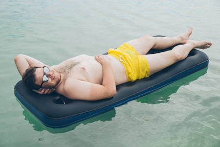 男子在海上的床垫上游泳。夏季时间概念