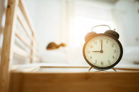 特写闹钟在床上醒来后, 阳光在清晨照片