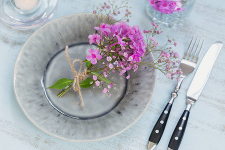 质朴的餐桌设置, 粉红色的花朵和蜡烛在轻木桌上。在普罗旺斯风格的节日装饰。浪漫晚餐顶部视图