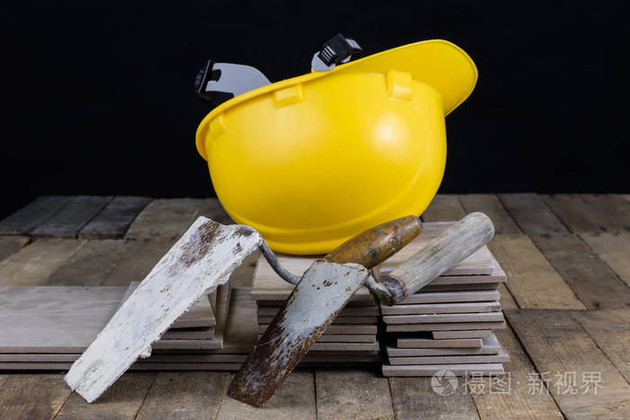 建筑用头盔,瓷砖和工具.建筑工人用木制车间的配件.深色背景