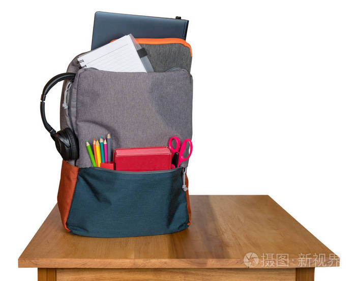 背包里充满了回到学校用品的木桌上, 并与白色背景隔离