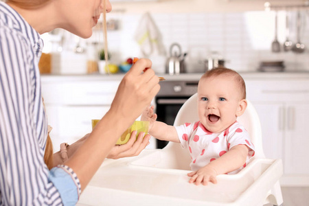 妇女喂养她的孩子在高脚室内。健康婴儿食品