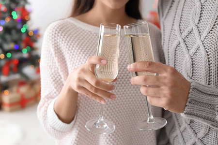 愉快的年轻夫妇与杯子香槟庆祝圣诞节在家