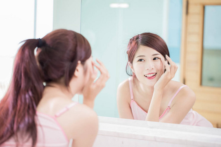 女人清洗浴室里的镜子美丽的女人看着镜子, 触摸她的眼睛在浴室里照片