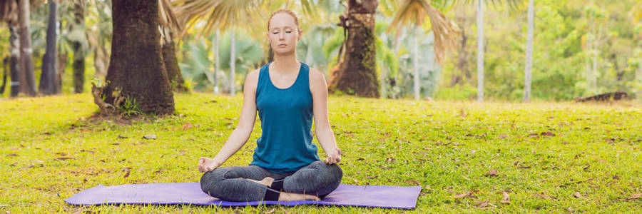 在热带公园里练习瑜伽的年轻女子。横幅, 长格式
