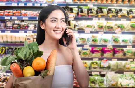 超市里拿着水果和蔬菜的购物纸袋的妇女