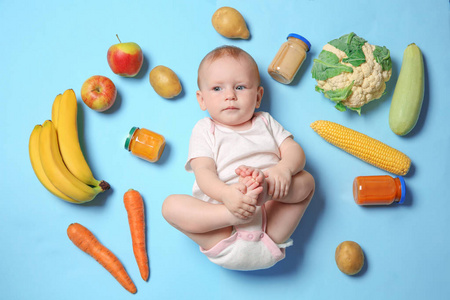 可爱的小孩子与配料和泥在罐子上的颜色背景, 顶部视图。婴儿食品