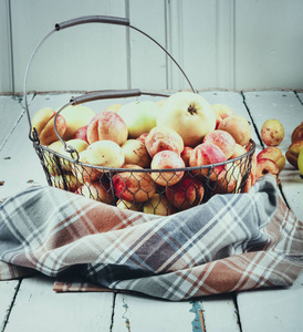 成熟可口的新鲜杏和苹果在木制桌上的金属篮子在房间里