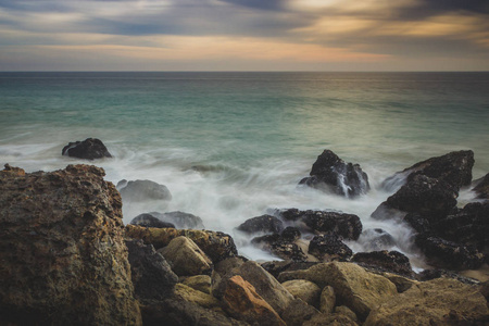 戏剧性的天空在日落沿点 Dume 状态海滩波浪碰撞成岩石形成沿海滩, 马里布, 加利福尼亚