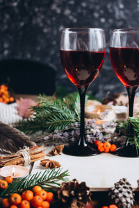 在玻璃杯, 红浆果, 颠簸和秋季树枝在木桌上的葡萄酒。秋季或冬季概念