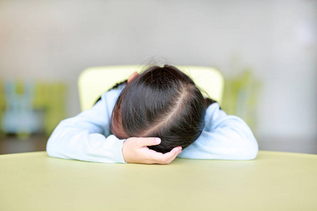 疲惫的小亚洲儿童女孩睡在孩子们的房间表照片