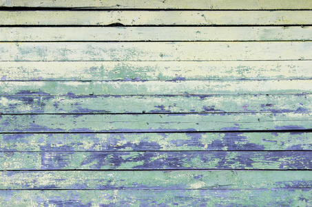 老式的木材背景与剥离黄色和绿松石旧的薄片油漆。老房子的墙壁