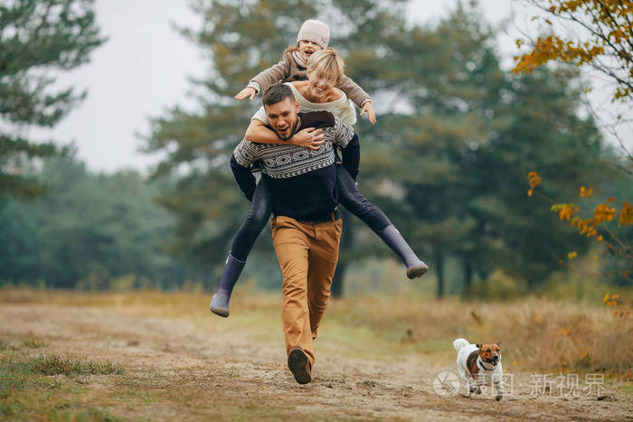 快乐的家庭有乐趣, 男人背着他的妻子和女儿在他的背后的森林小路上的