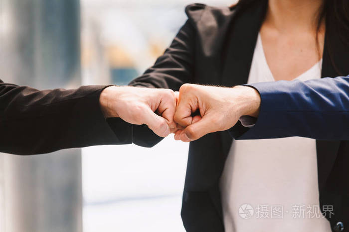 合作的商人和合作伙伴给拳头碰手.成功的团队合作理念