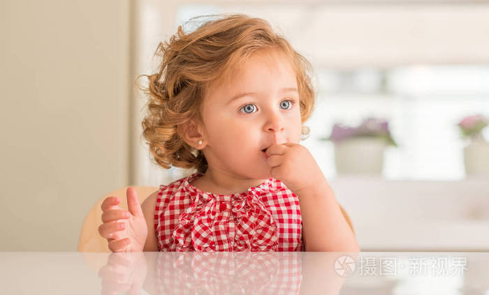 美丽的金发碧眼的孩子在家里吃糖果