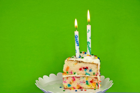彩虹绿背景蜡烛的生日蛋糕片