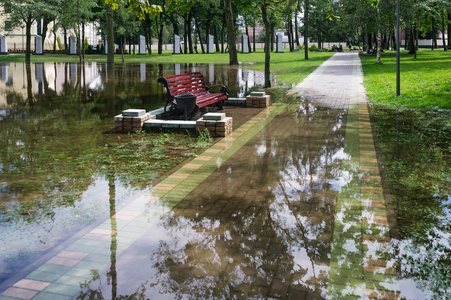 公园里的人行道和长凳上, 雨水淹没了水。水平照片