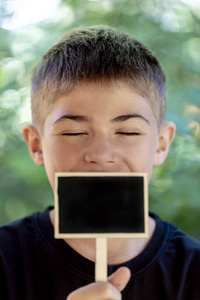 青年的脸特写, 少年拿着一个黑色的木标牌在嘴上