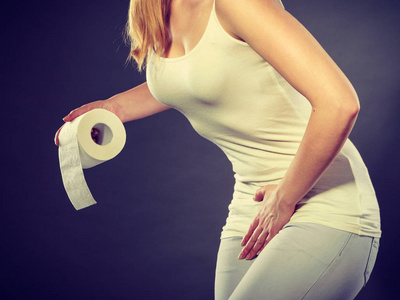 女性尿失禁生病的女人用手按住她的胯部的下腹部,拿着纸卷.