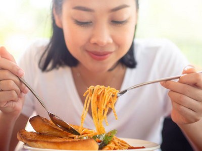 亚洲妇女近距离吃意大利面。聚焦意大利面