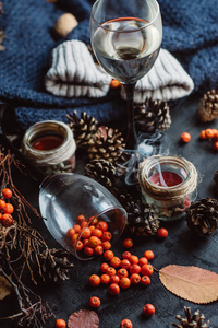 酒在杯子, 红色莓果, 颠簸和秋天分支在黑桌。秋季或冬季概念