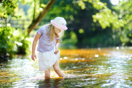流的暑假在炎热的夏日, 一个可爱的小女孩在河边玩耍.