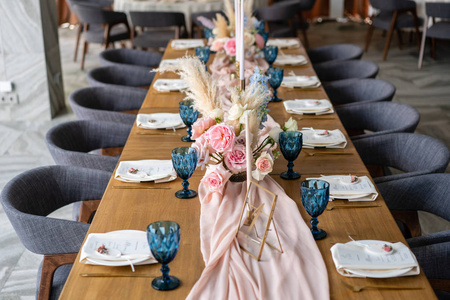美丽而精致的婚礼庆典装饰。宴会桌上有米色的粉红色桌布盘子和烛台和蜡烛。