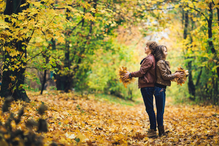 秋天的爱幸福的情侣在公园里捧着秋天的枫叶在手中