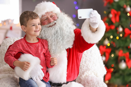 真正的圣诞老人采取自拍与小男孩室内