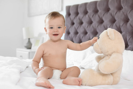 可爱的小宝宝与泰迪熊在床上在家