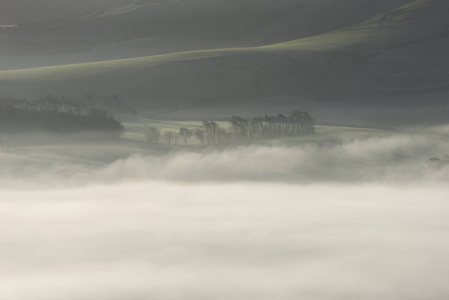 美丽的雾英国乡村风景在日出在冬天与层数滚动通过领域