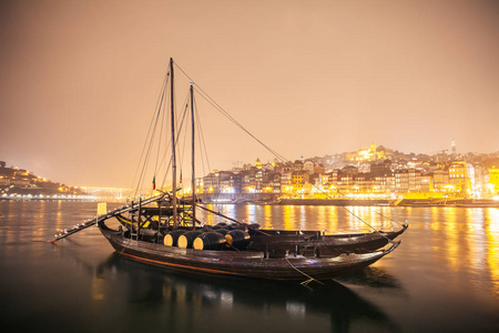 传统的 rabelo 小船在晚上在波尔图平静的水与反射在水中