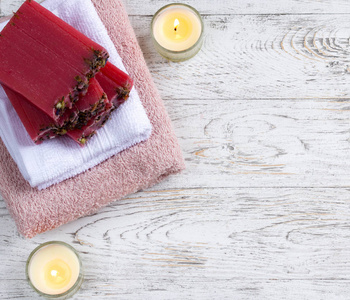 手工肥皂在毛巾上用白色木桌上的蜡烛。美容 spa 的治疗和放松的理念。顶部视图