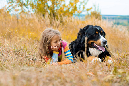 女孩躺在大狗旁边的秋天散步 Berner Sennenhund