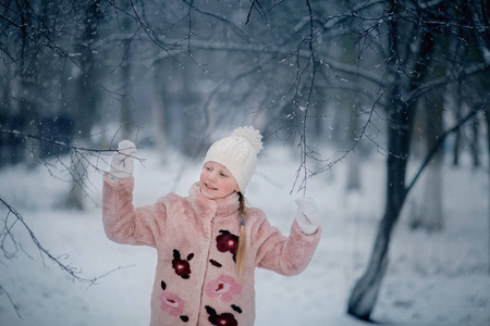 在雪地里玩毛皮大衣的女孩
