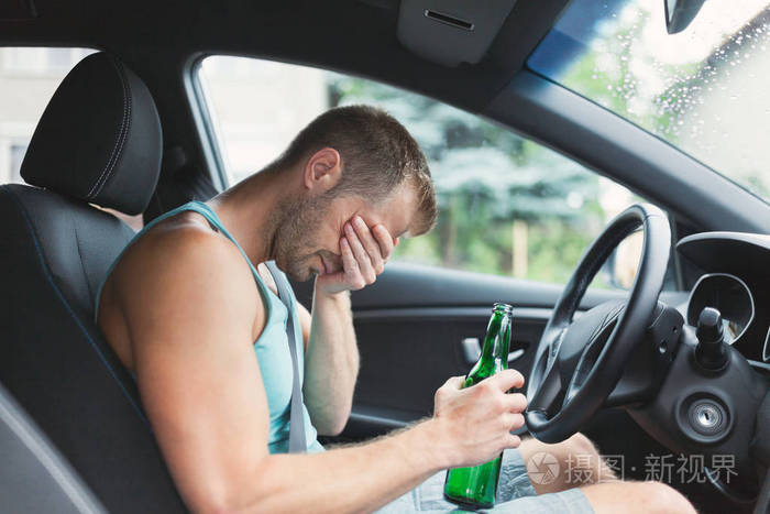 酒后驾车者在汽车方向盘后面喝酒照片-正版商用图片0us9cu-摄图新视界