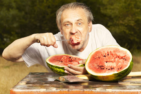 夏天雨天, 人们在餐桌上吃西瓜提神.照片