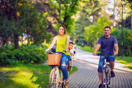 幸福的家庭。微笑活跃的父亲和母亲与孩子在自行车在公园乐趣。家庭体育与健康生活方式
