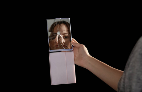 年轻漂亮的女孩看着破碎的镜子黑色背景破碎的镜子玻璃碎片